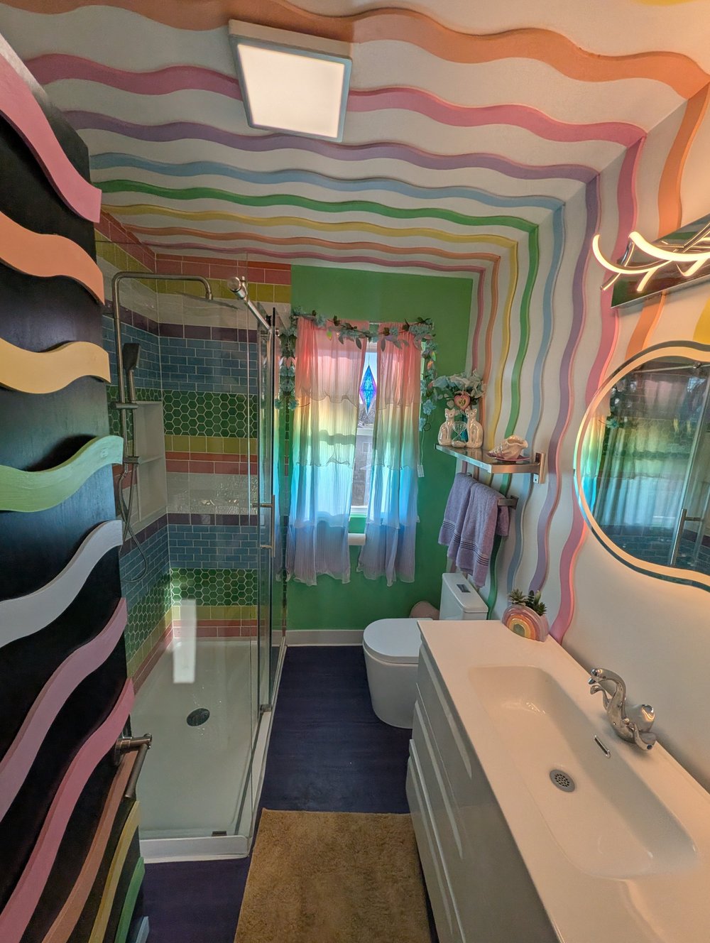 Pastel bathroom with rainbow wavy walls and LED mirror
