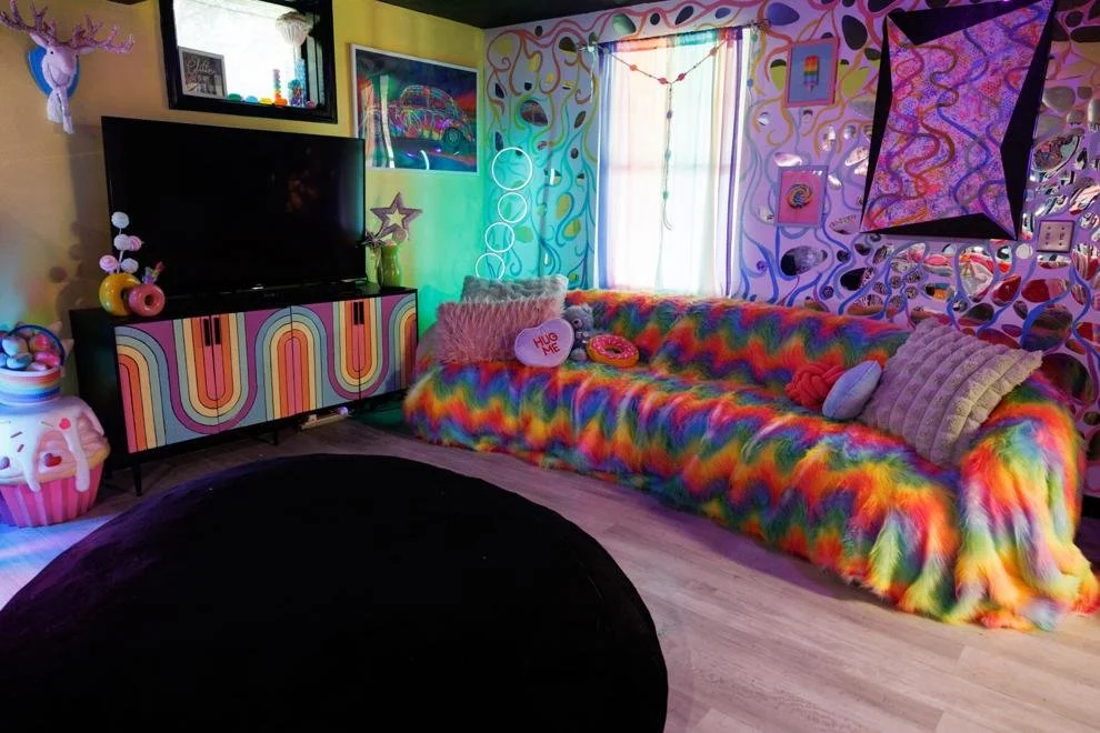 Candyland lounge with rainbow fur sofa and glowing TV wall