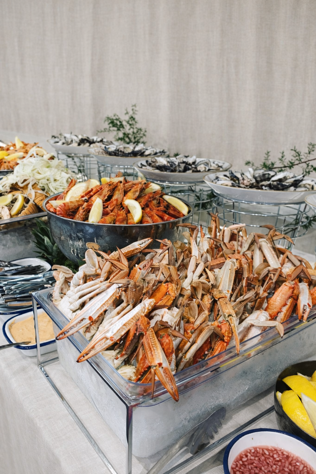 Seafood buffet featuring lobsters, oysters, and prawns, crabs and garnished with lemon wedges and served with dipping sauces.