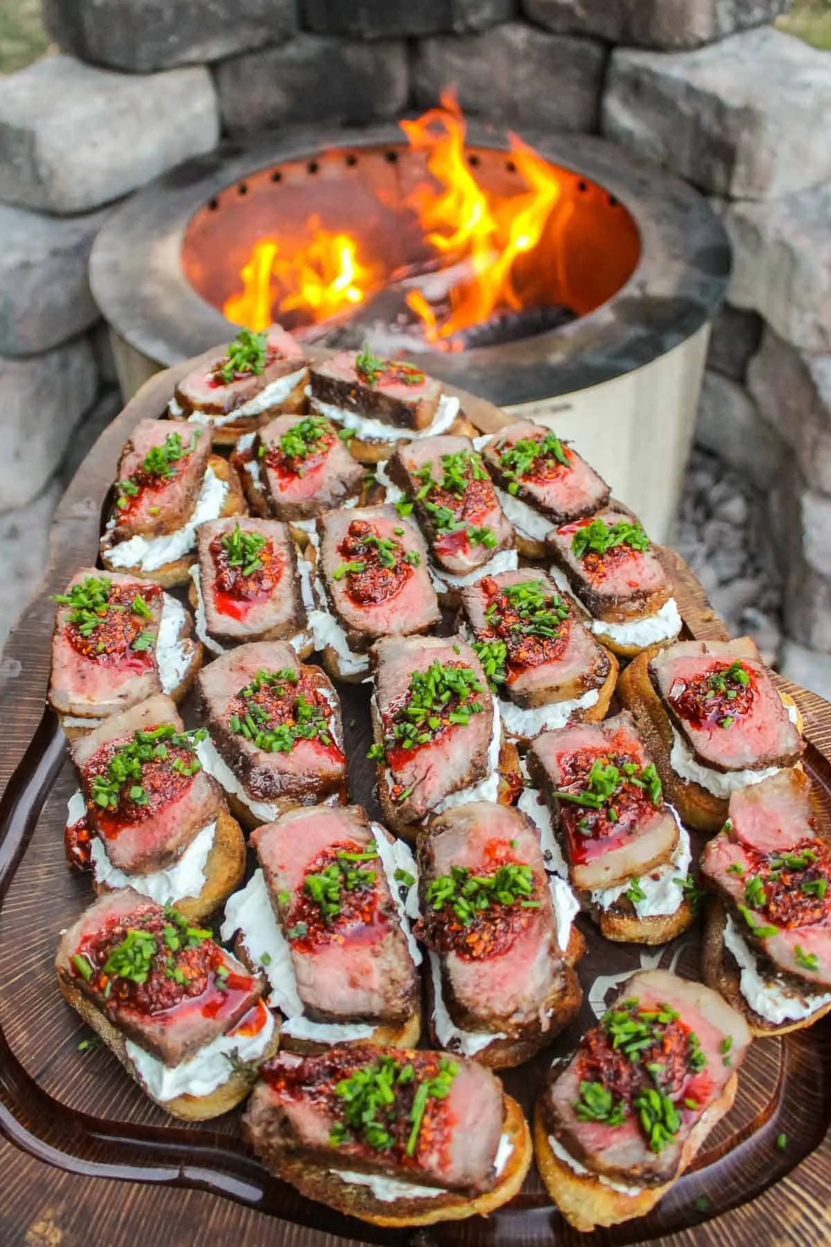 Mana Kai canape bark seared beef served on crostini topped with radish cream, garnished with green herbs salsa, placed on a wooden platter near an outdoor fire pit.
fire cooking catering Sydney, private chef open fire Sydney, Mana Kai Sydney Private