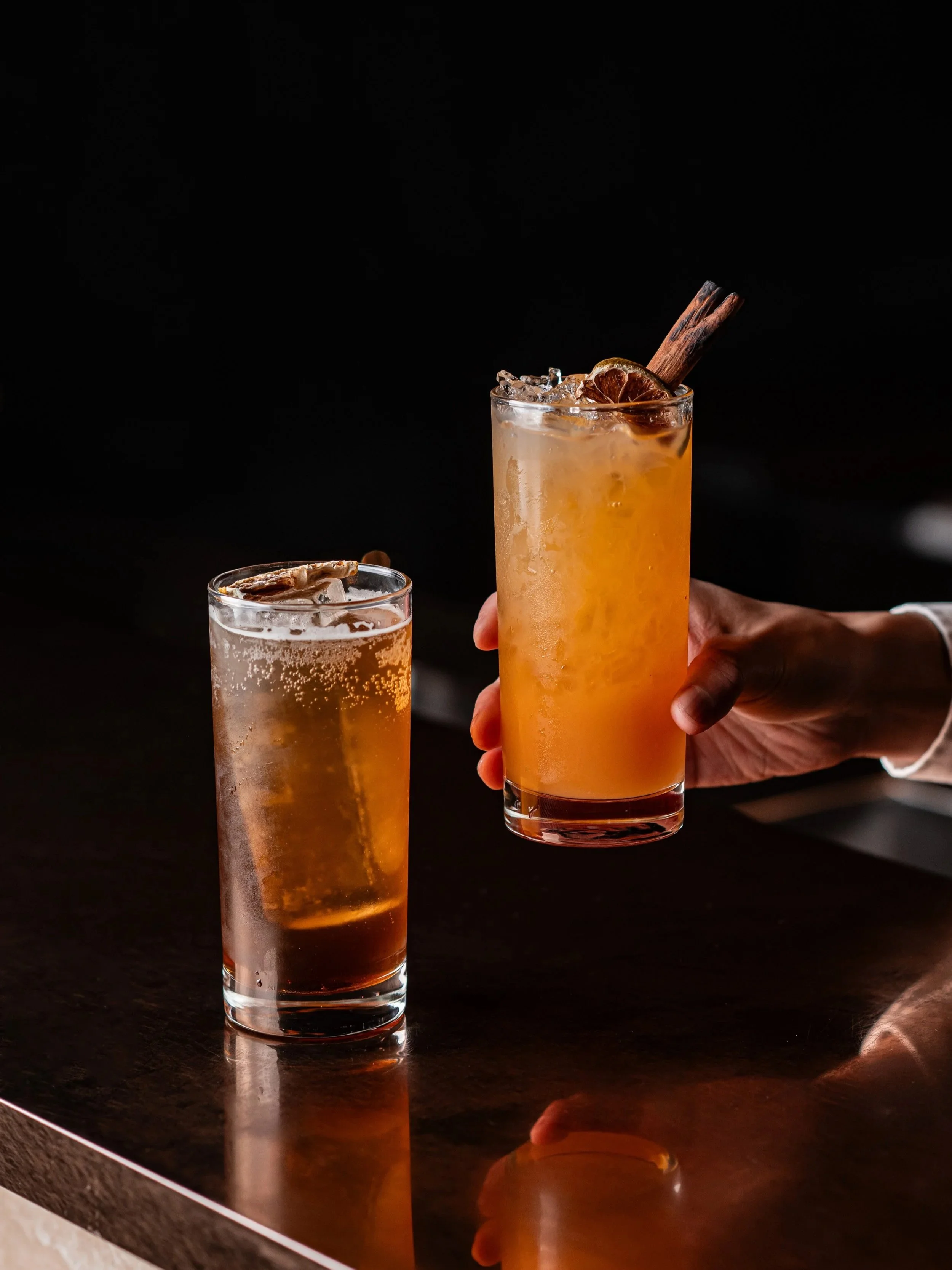 Picture of two cocktails, an Oolong Iced Tea and Tropical Sunset.