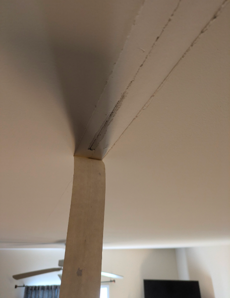 Structural ceiling drywall cracks around support beam before repair