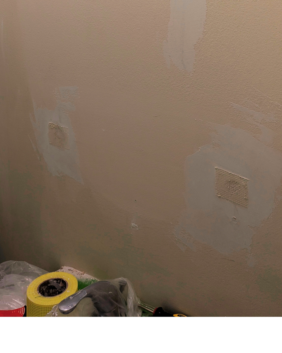 Residential bathroom wall with Wall patches and coats of drywall compound for repair 
