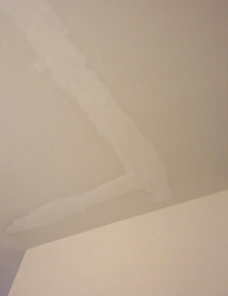 Ceiling water damage in the repair process showing one coat of drywall compound applied with tape