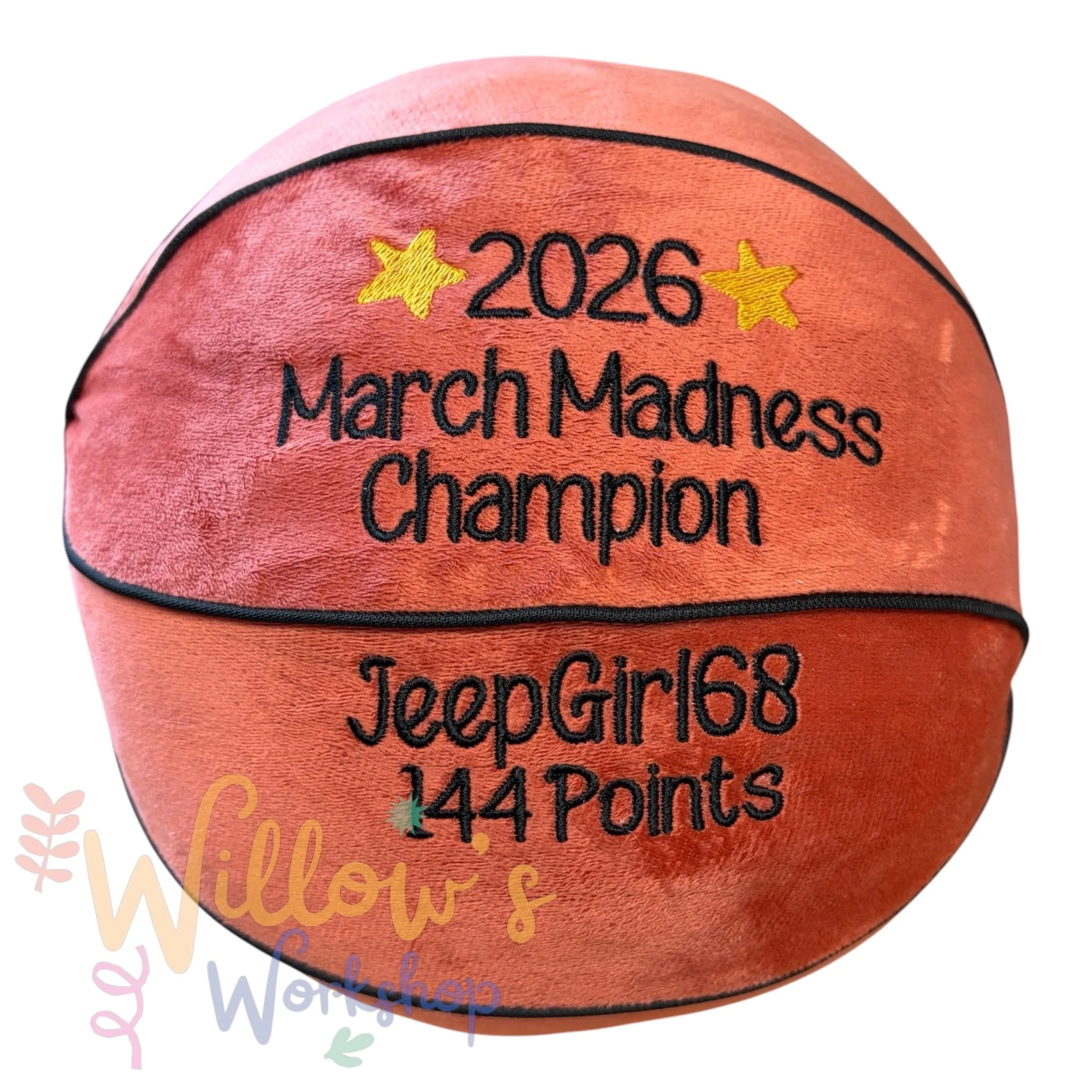 Close-up of a pink volleyball with embroidered text and yellow stars, reading "2026 March Madness Championship".