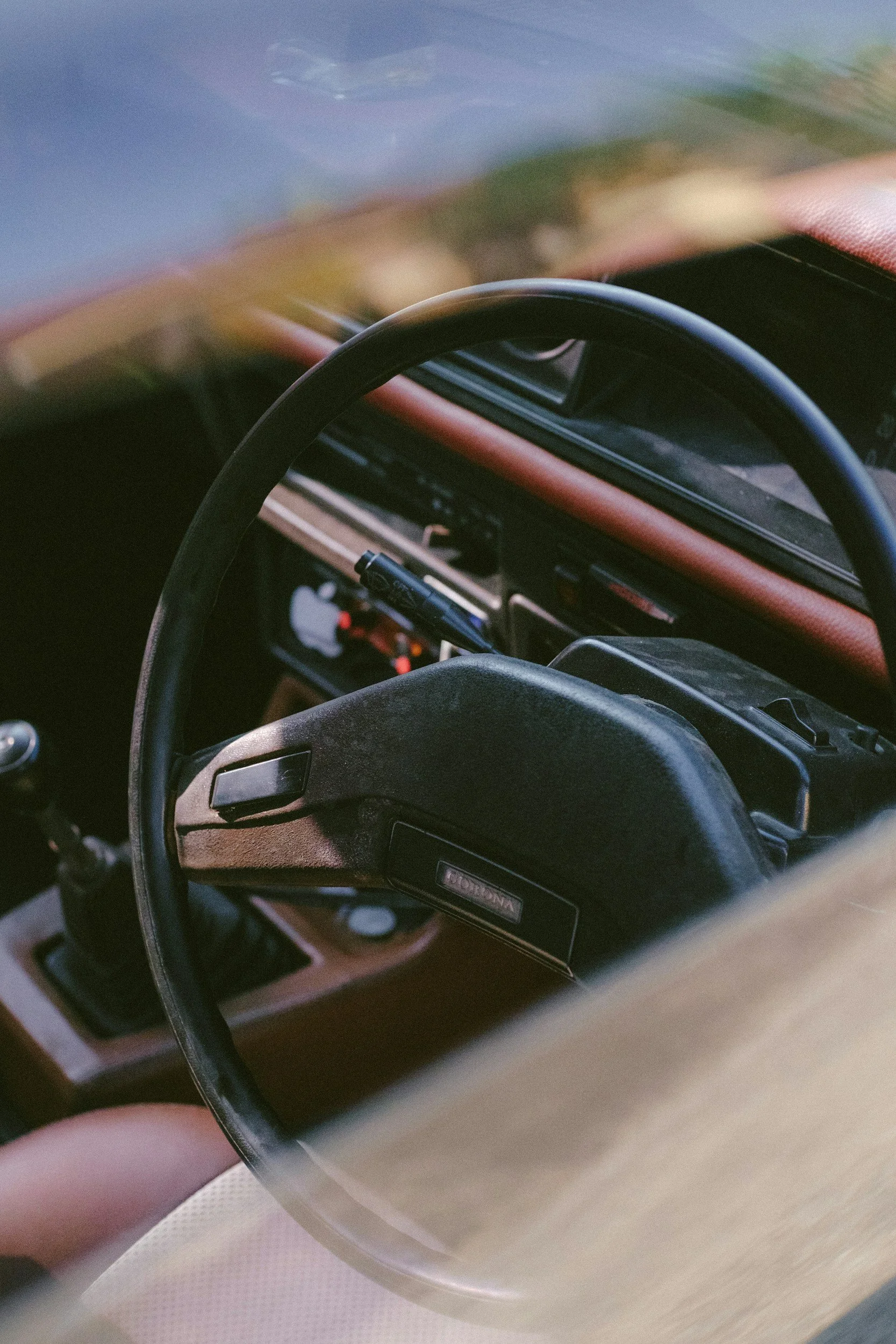 Close-up of the interior of a vintage car, showing the steering wheel, dashboard, and gear shift.