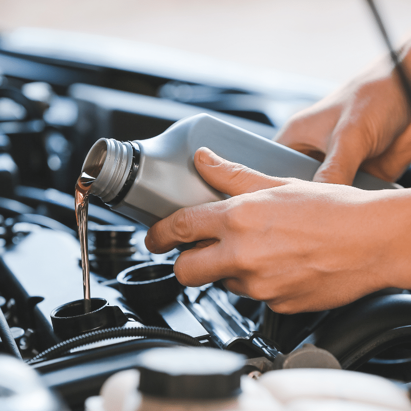 Person pouring motor oil into a car engine.