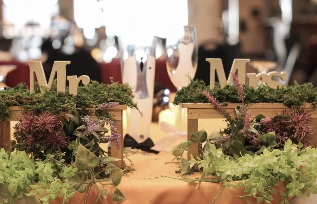 Wedding table centerpieces with wooden boxes filled with greenery and purple flowers, decorated with 