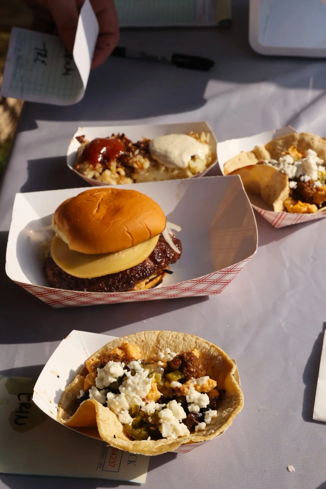 A tray of Mexican food including a hamburger, tacos, and two small dishes of Mexican dishes.