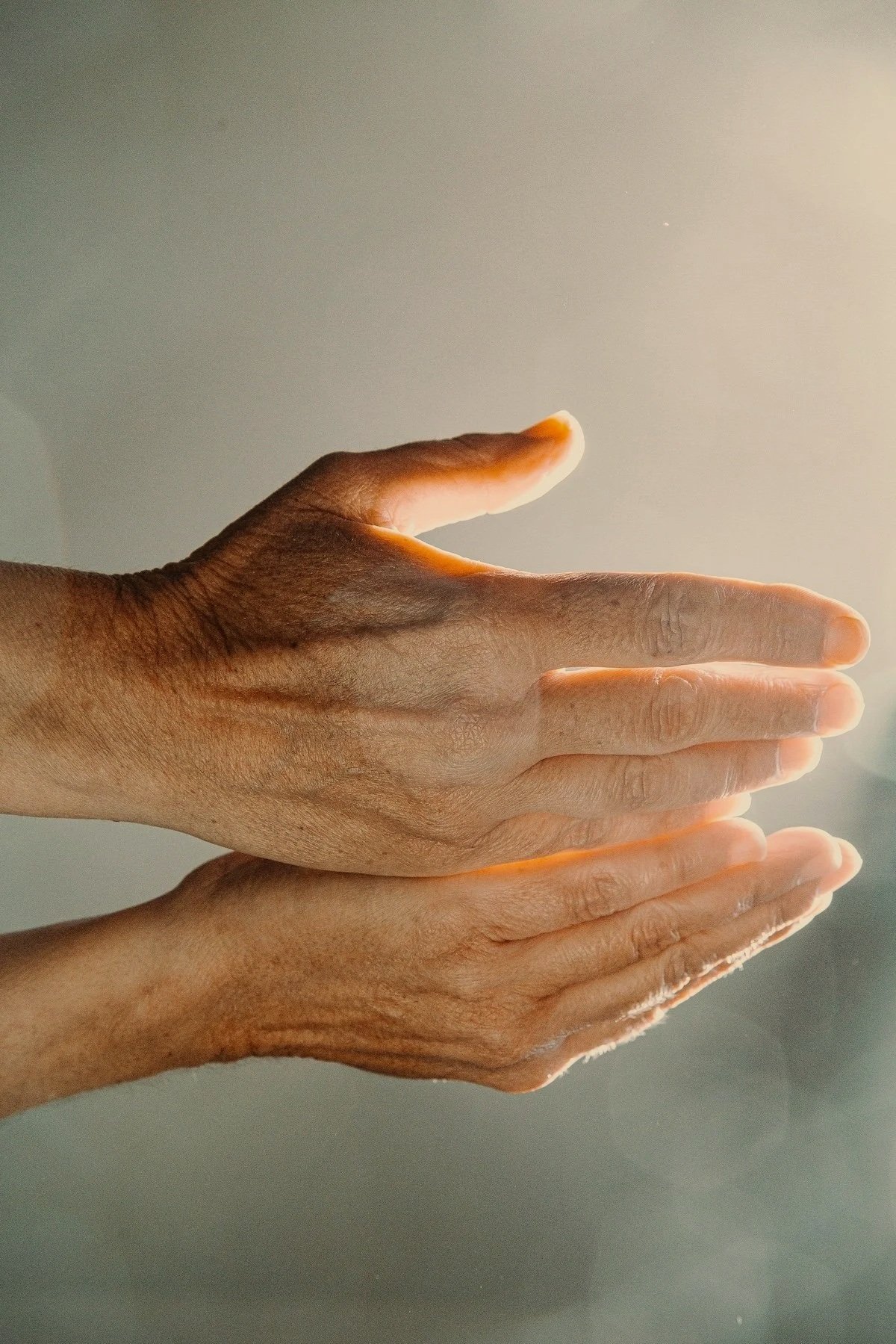 Two hands, one darker-skinned and one lighter-skinned, overlapping each other in a gentle gesture.