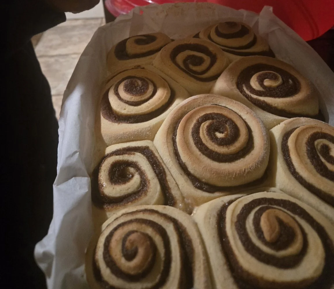 A tray of freshly baked cinnamon rolls with a spiral pattern of cinnamon filling.
