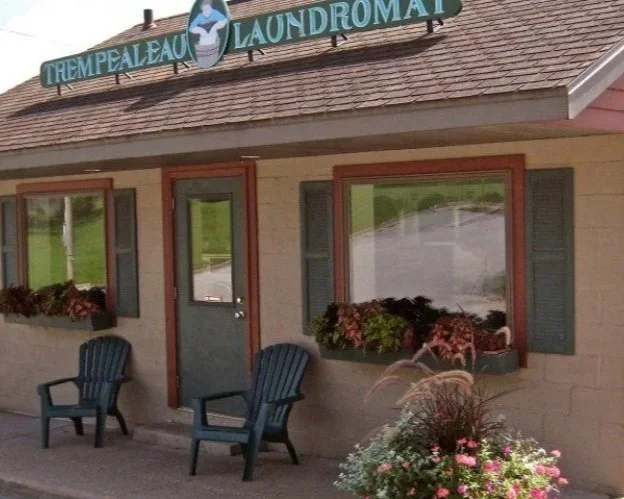 A photo of Maas Laundries building, a light pink cinder block building with green and red trim.