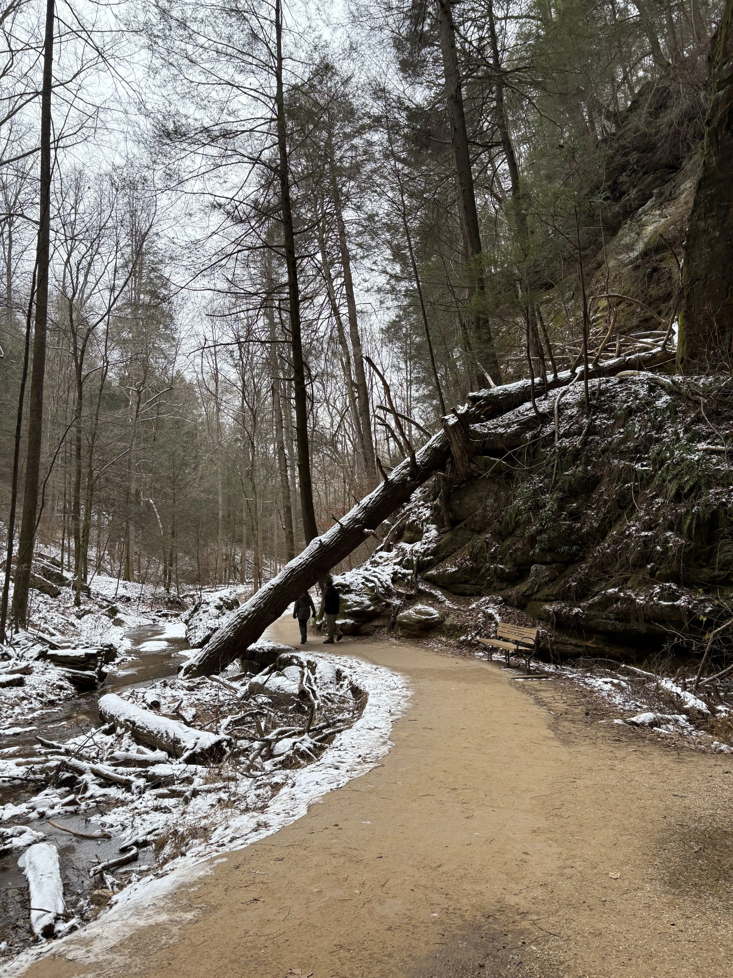 Two hikers on a sandy path with snow