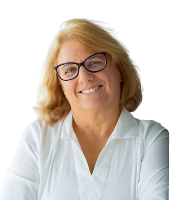 A smiling middle-aged woman with blonde hair, wearing glasses and a white collared shirt, against a black and gray background.