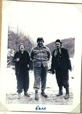 Three women standing outdoors in winter, wearing warm clothing, with snow on the ground and trees in the background.