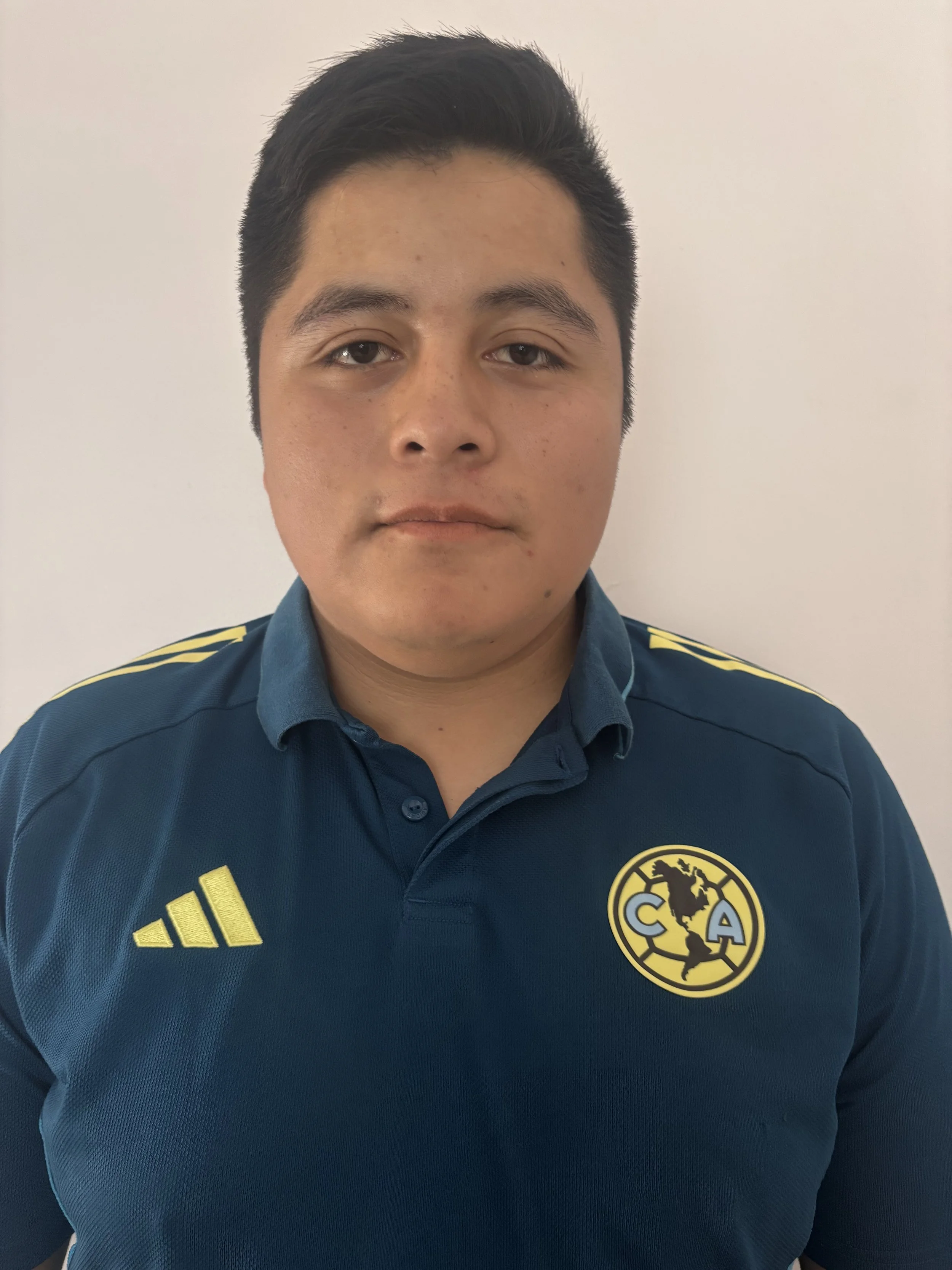 Joven con camiseta azul del club América, frente a una pared blanca