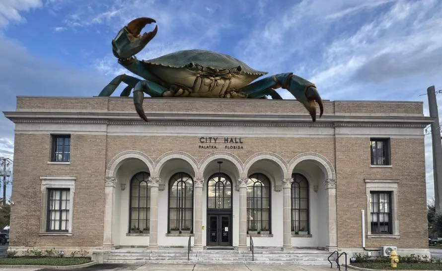 Large sculpture of a crab on top of the city hall building in Palatka, Florida, with a blue sky in the background.