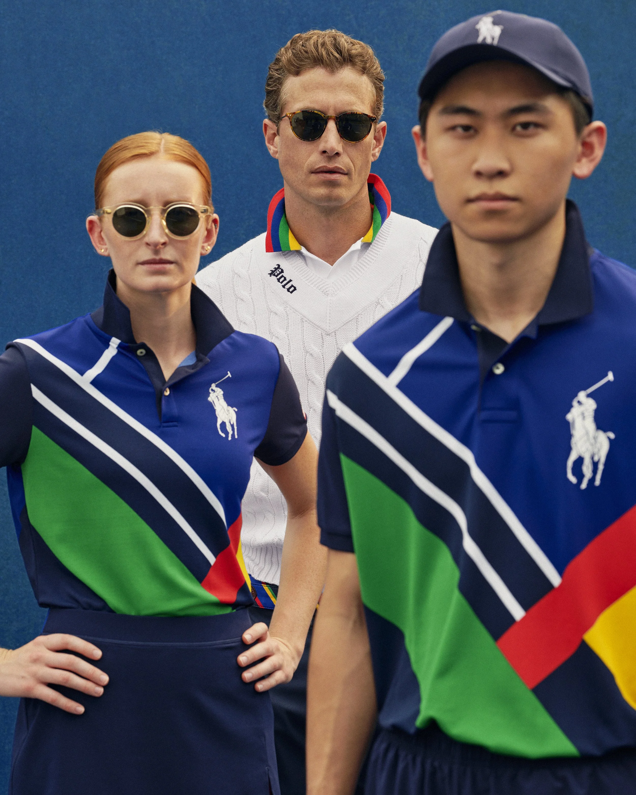 3 figures standing on tennis court front male and female wearing a printed polo featuring an abstract tennis court for the us open ball person uniform