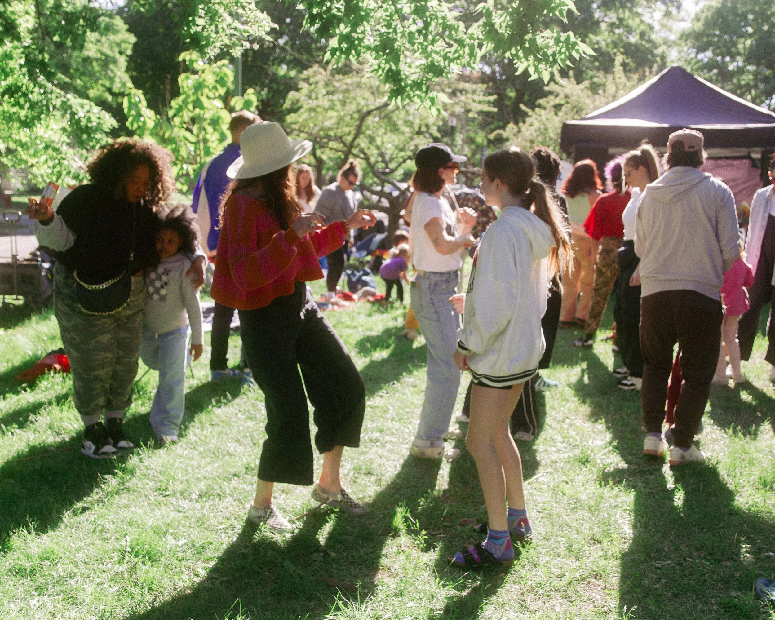 People dancing outdoors in a park on a sunny day.