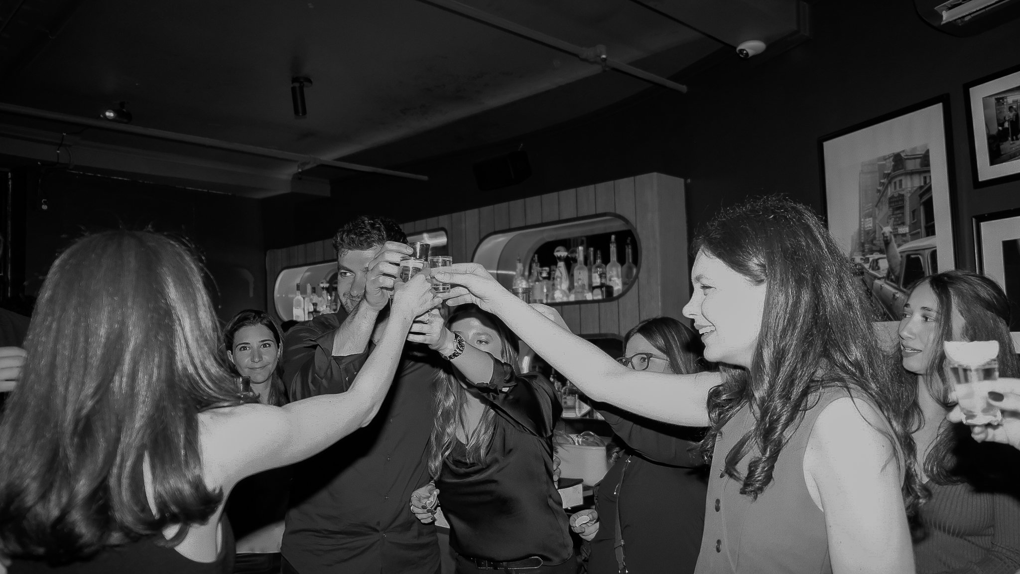 A group of people at a bar or restaurant raising glasses in a toast, smiling and enjoying their time together.