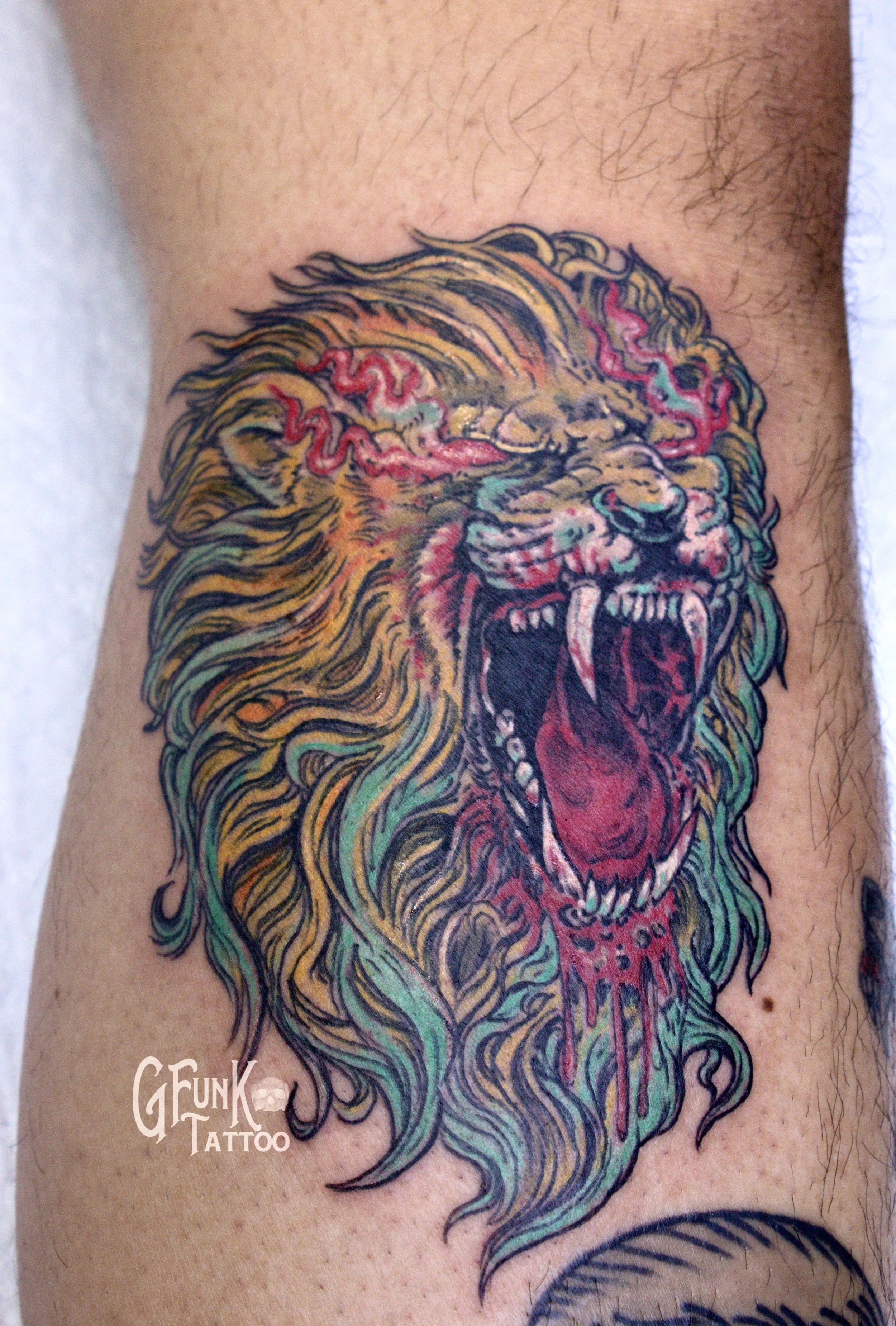 Tattoo of a fierce lion's face with colorful details on a person's arm.