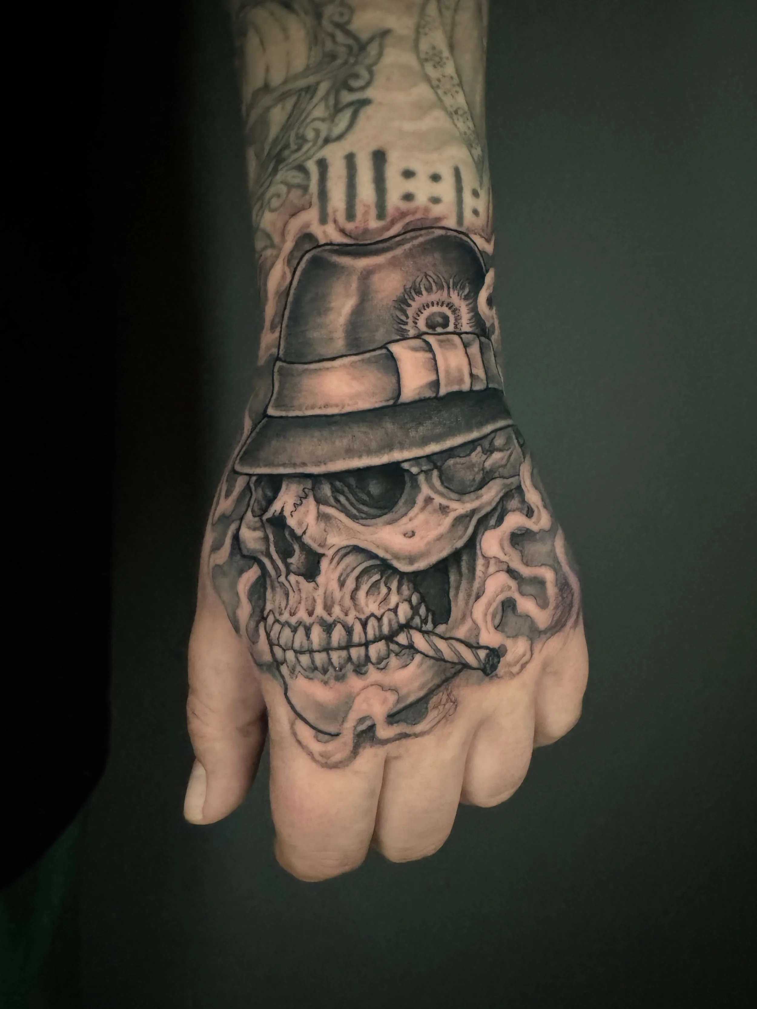 Tattoo of a human skull with smoke surrounding it, located on a person's arm.