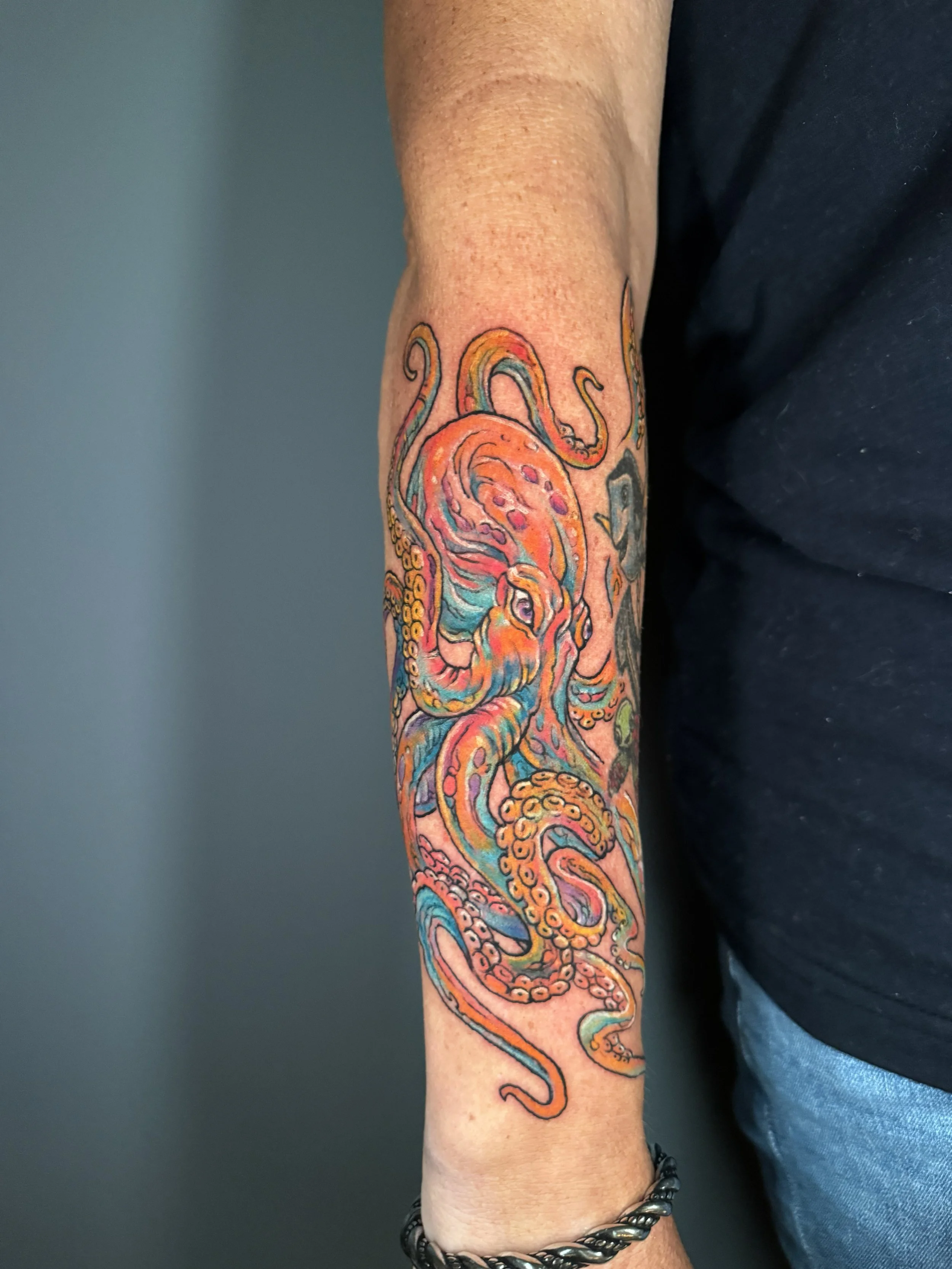 Colorful tattoo of an octopus on a person's forearm.