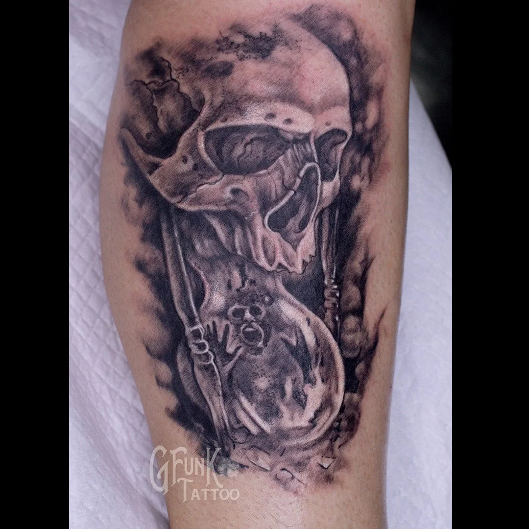 Black and gray tattoo of a human skull with wings and a snake wrapped around a heart-shaped object.