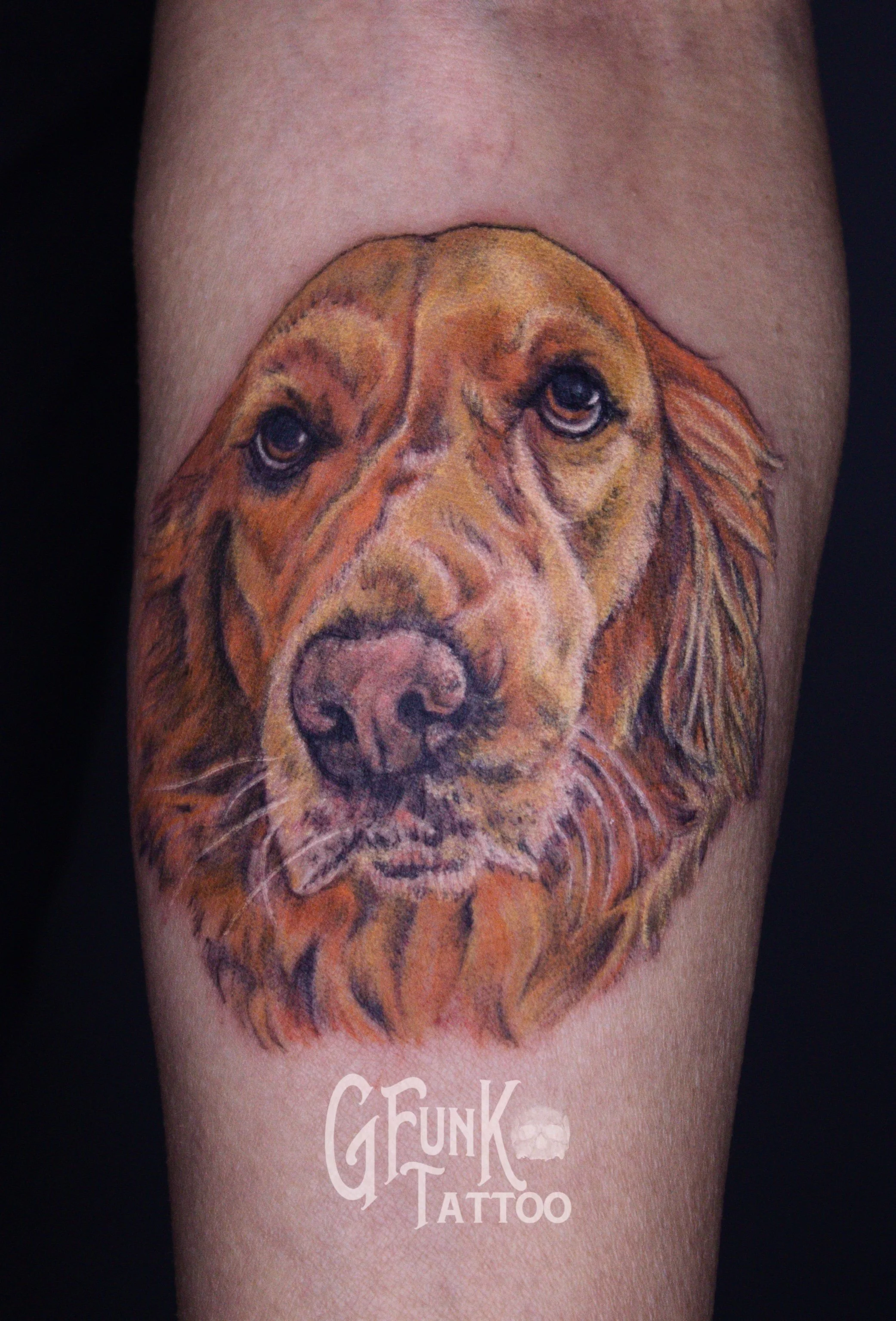 Tattoo of a realistic dog’s face on person’s arm, with the words "GEE FUNG TATTOO" in white below it.