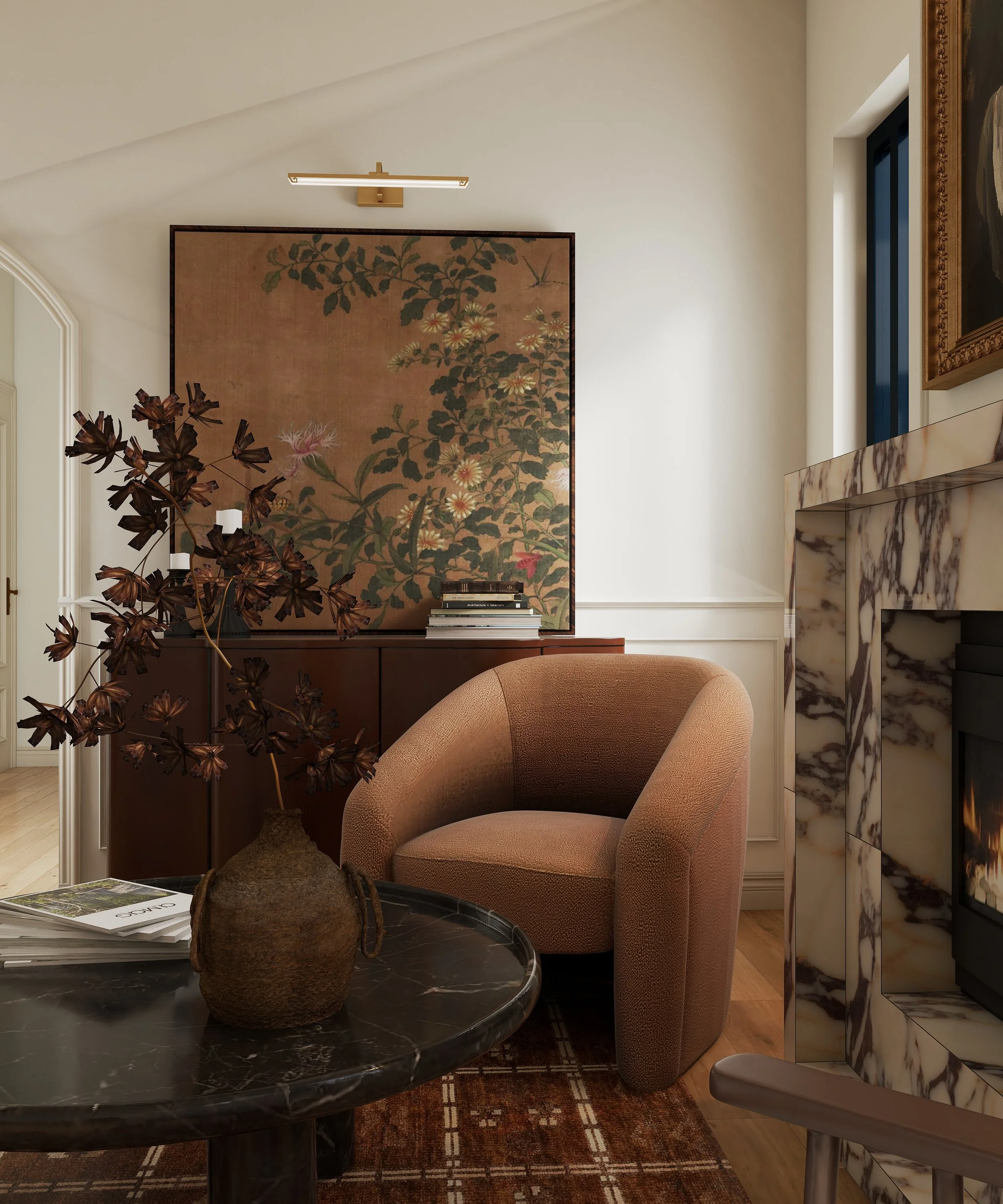 A cozy interior corner featuring a round marble table with a brown textured ottoman, an orange upholstered armchair, a vintage wooden cabinet, a large floral painting on the wall, and a marble fireplace. Natural light streams through a narrow window.