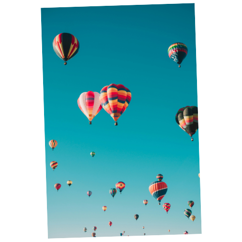 Multiple colorful hot air balloons floating in a clear blue sky.