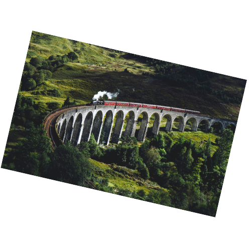 A steam train traveling across a curved stone bridge in a lush, green landscape.