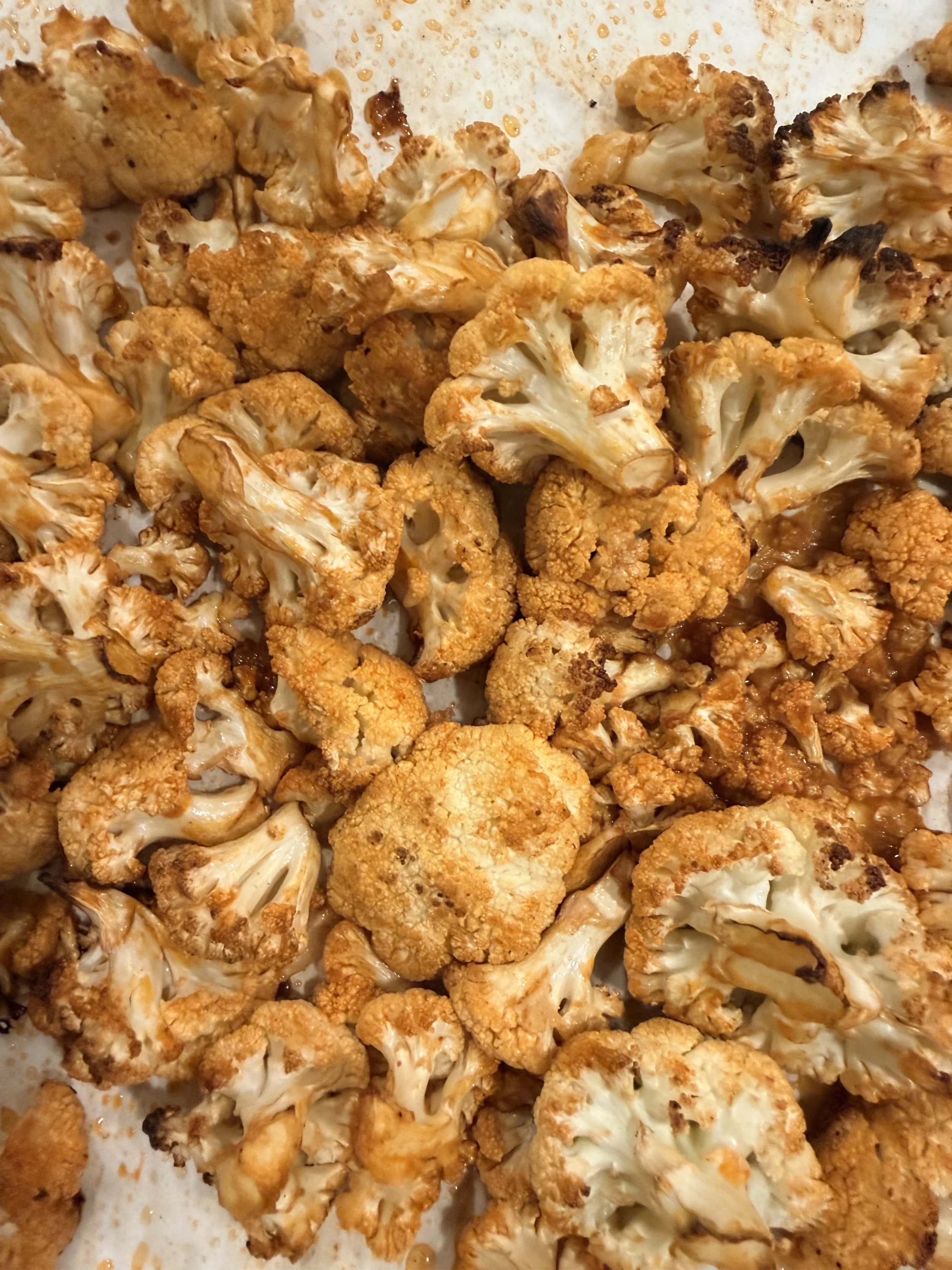 Roasted cauliflower florets, golden brown and baked on a sheet pan.