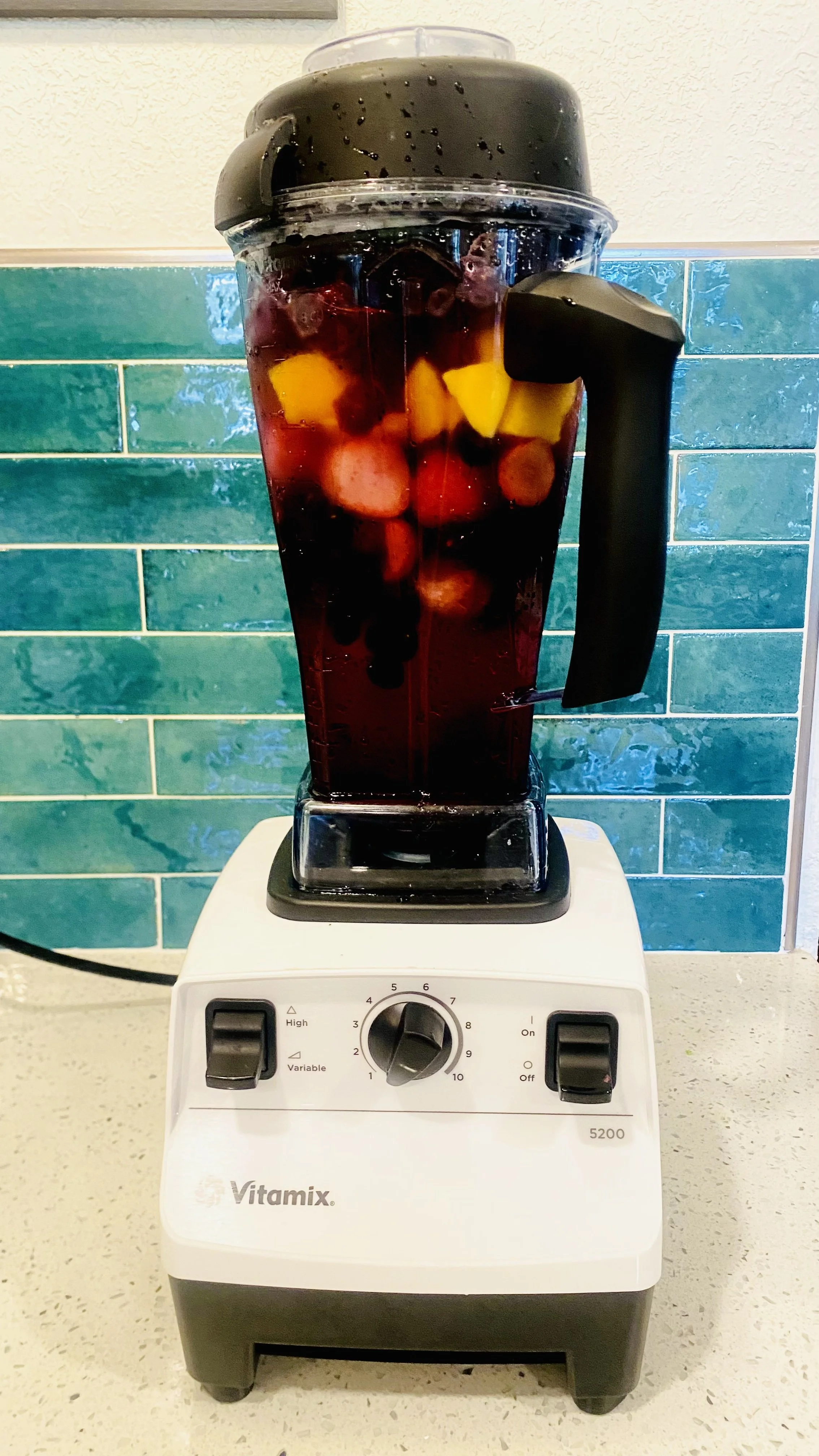 Blender filled with a dark red liquid and assorted fruit pieces.