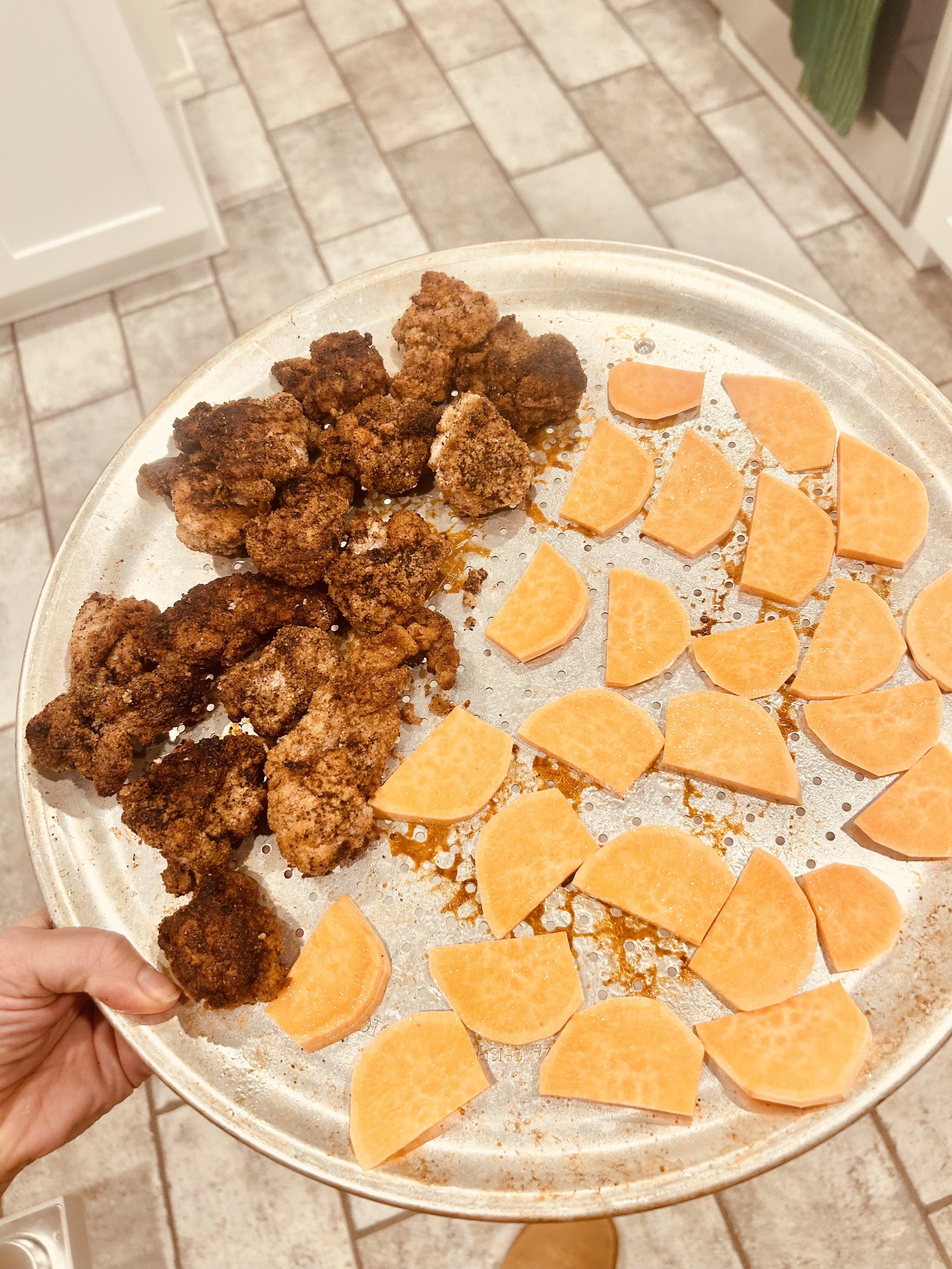 A metal tray with fried chicken pieces and sliced sweet potatoes.