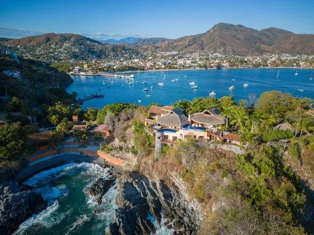 Residencias, vegetación, vialidades y costa en una zona residencial de Zihuatanejo.