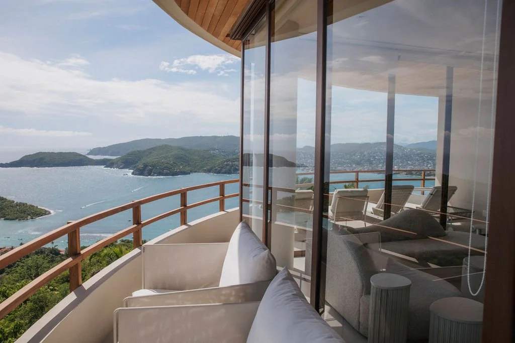 Balcony with lounge chairs overlooking a sea and islands.