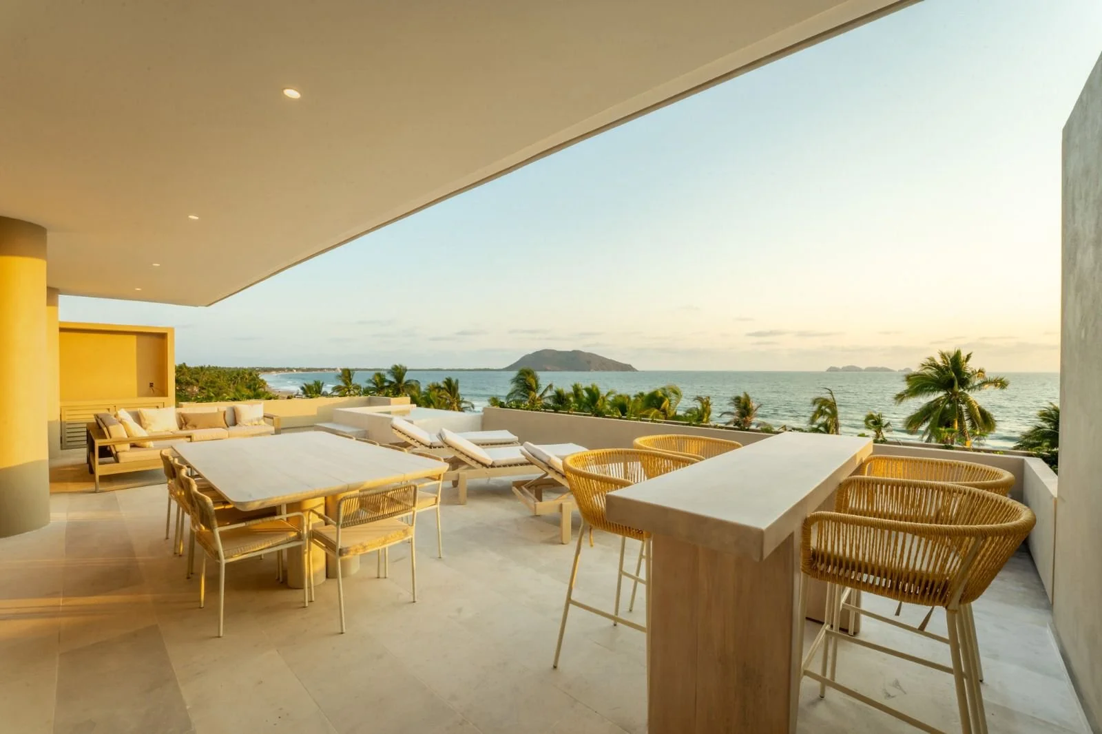 Terraza amueblada y techada conectada con los espacios interiores de una residencia costera.