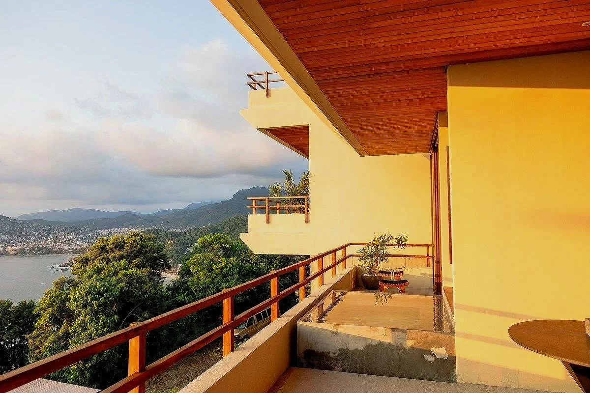 Terraza residencial conectada con espacios interiores y rodeada de vegetación tropical.