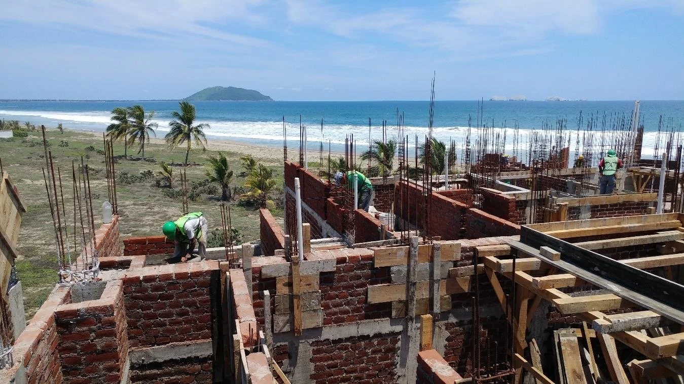 Coastal residential development under construction in Mexico showing multiple stages of completion.