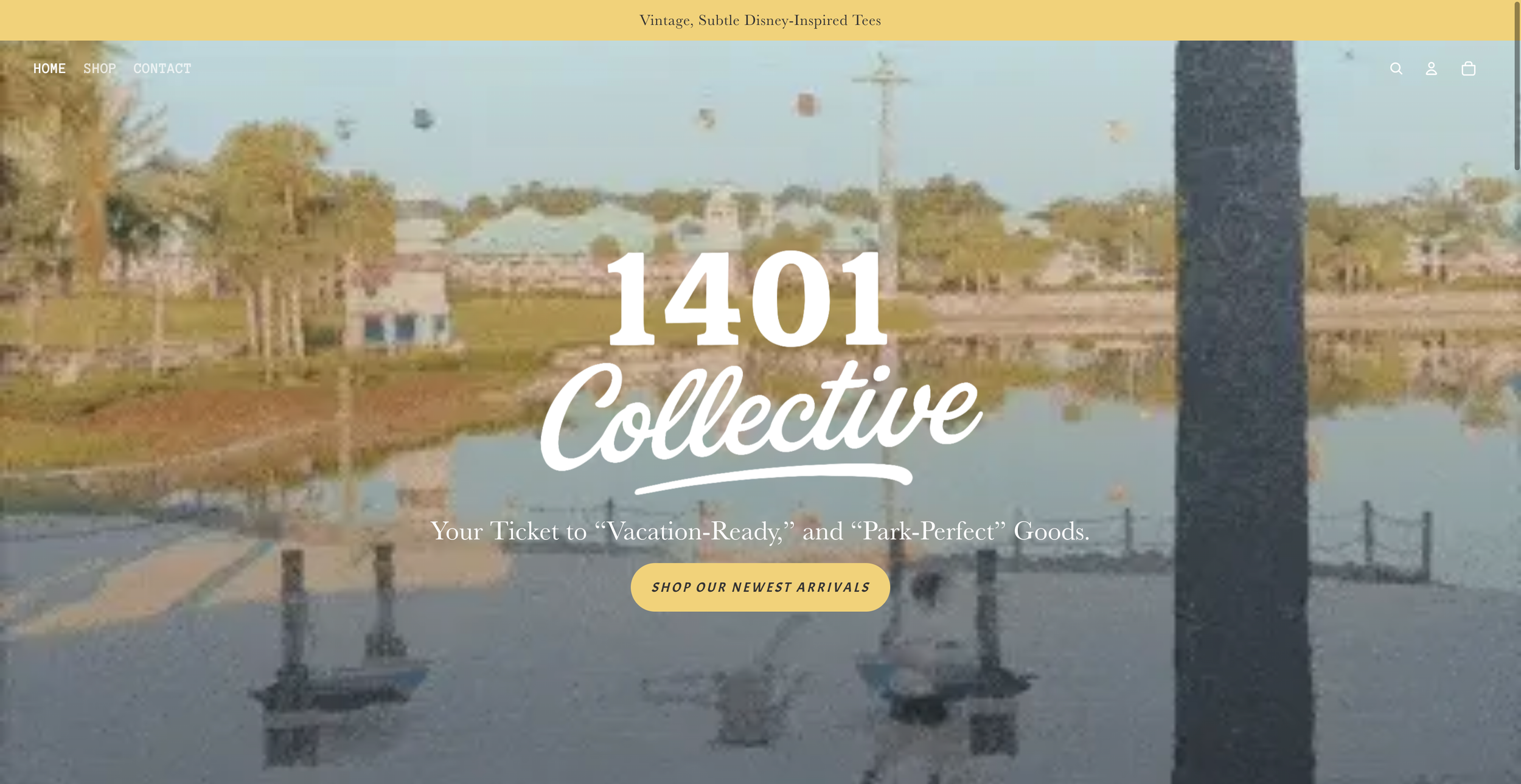 A website homepage for 1401 Collective, a clothing brand specializing in vintage, Disney-inspired tees. The background shows a scenic view of a lake with trees, houses, and a power line. The page features navigation options for Home, Shop, and Contact, and includes a call-to-action button that says "Shop Our Newest Arrivals."