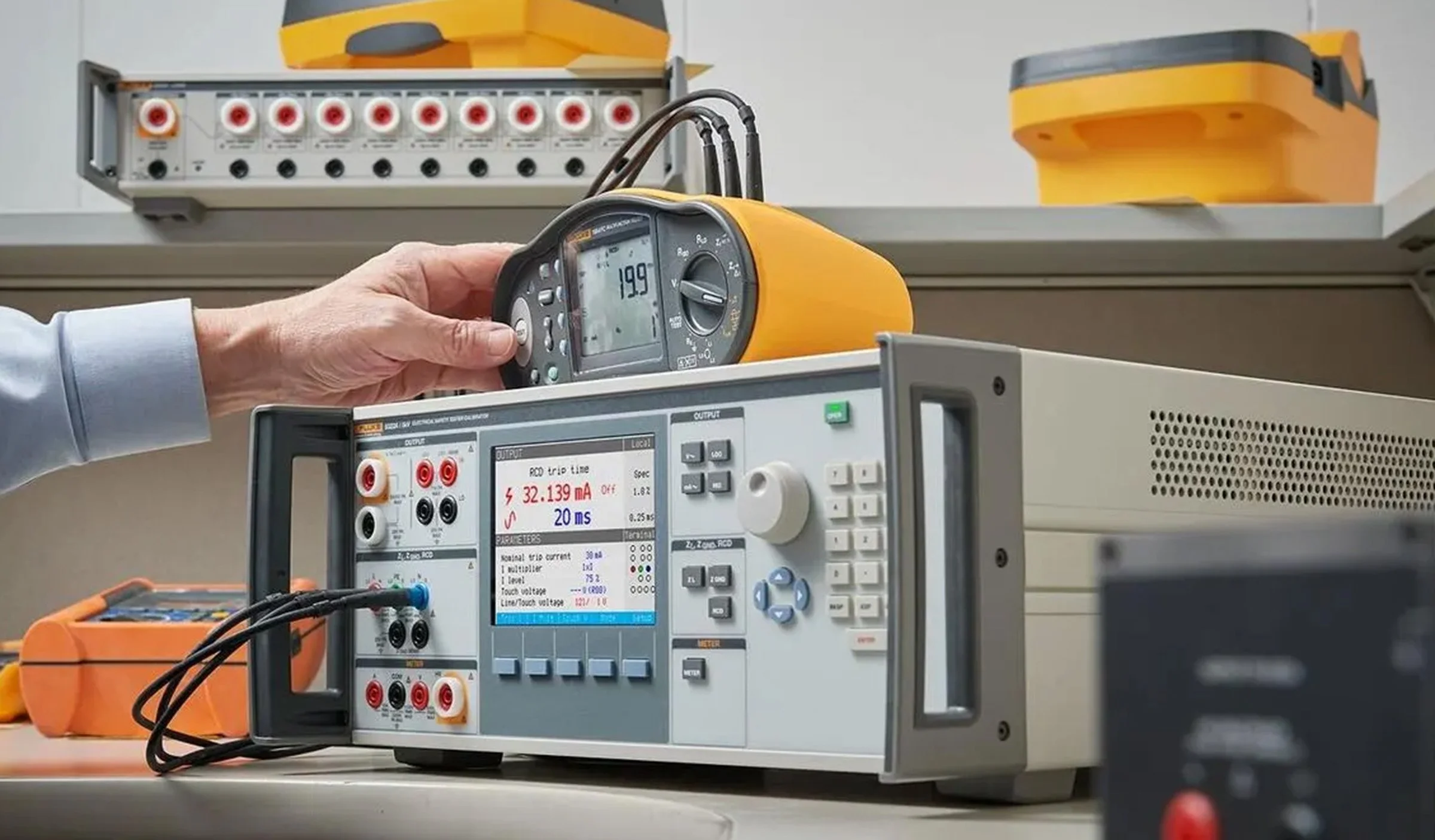 A person measures electrical parameters with a digital multimeter and an electrical testing instrument in an electronics laboratory.