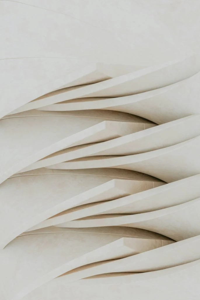 Close-up of overlapping cream-colored architectural panels with curved, flowing shapes.