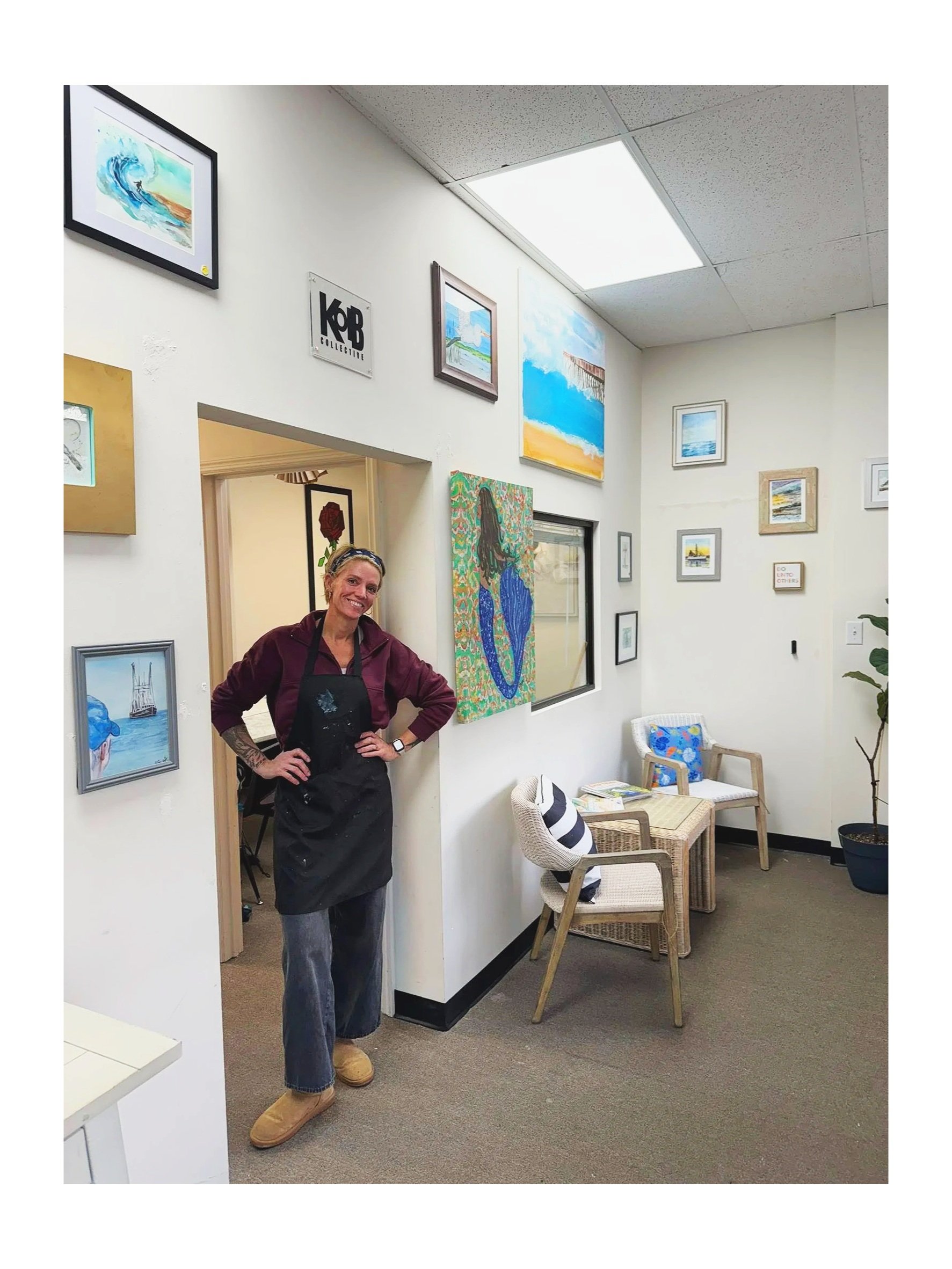 Woman standing in an art gallery with various paintings on the wall.
