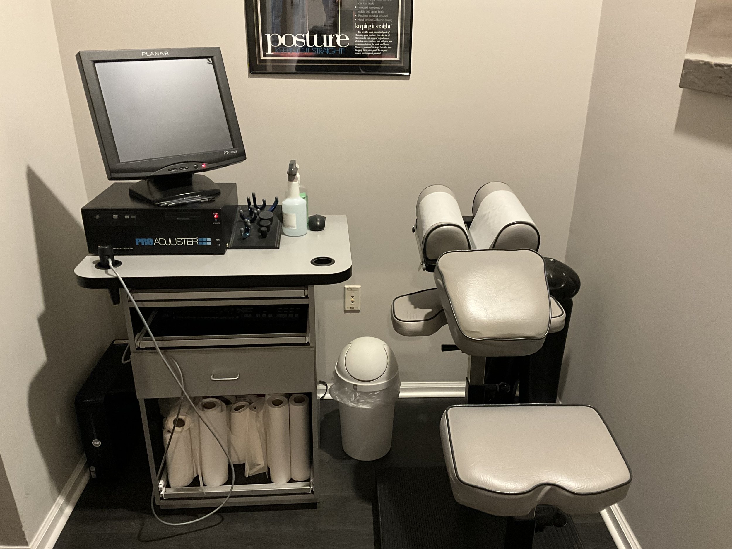 Medical examination room with a chair, a computer, and medical supplies.