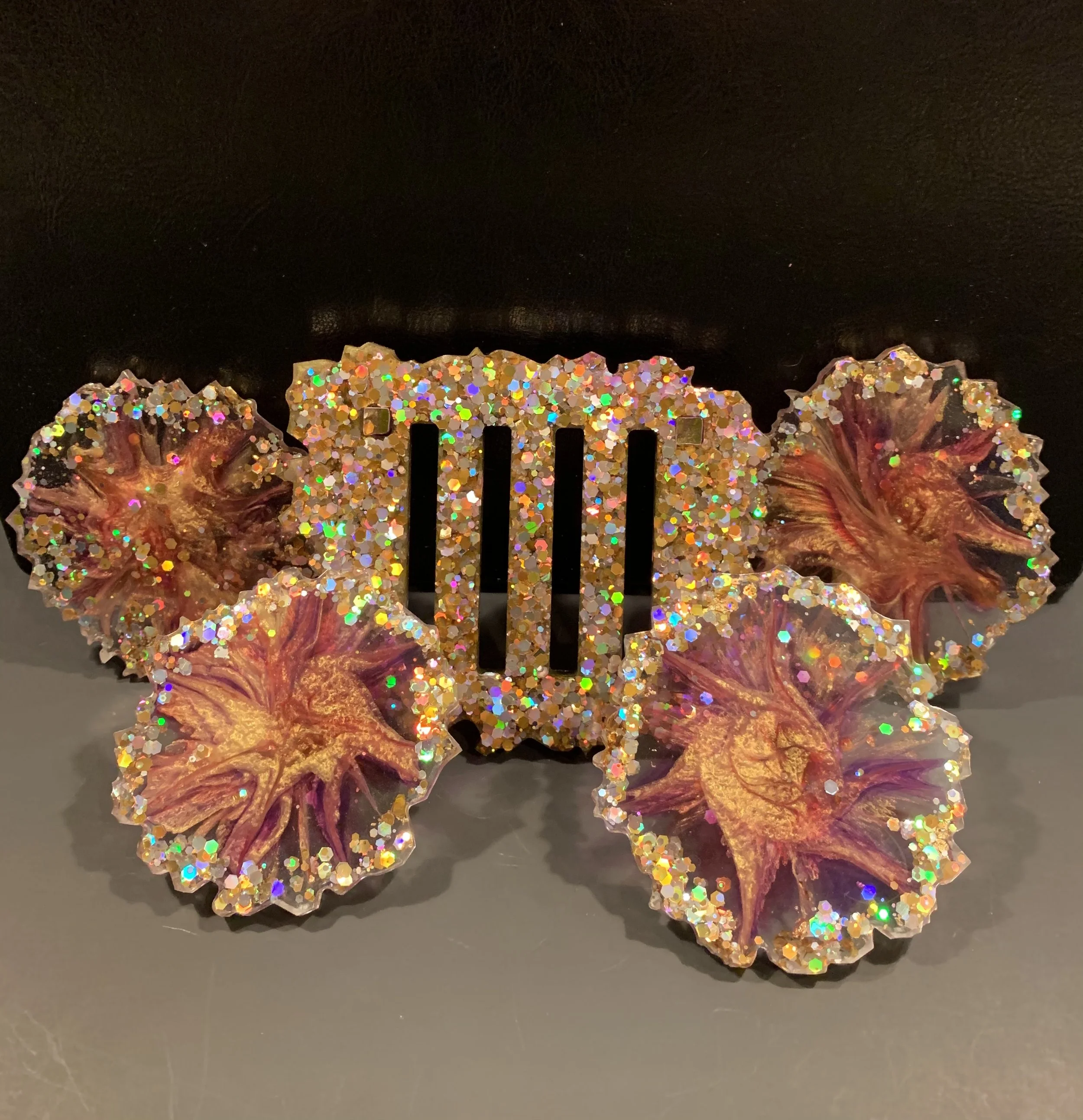 A glittery hair clip with a gold, purple, and pink starfish design, decorated with multicolored rhinestones.