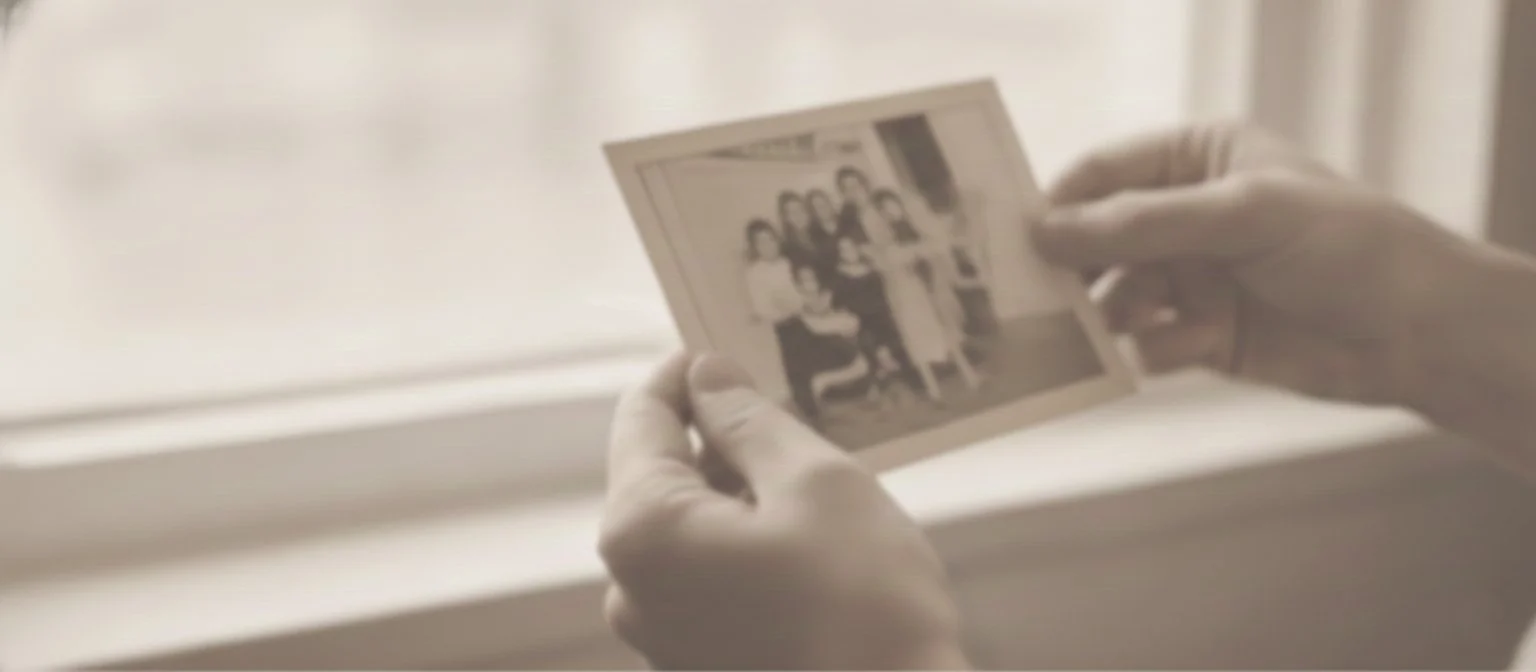 A person holding a black and white photograph of a group of people.