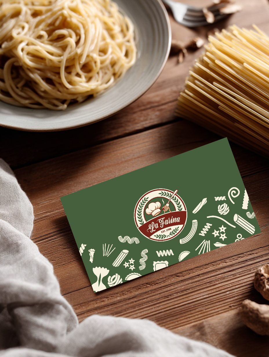 A plate of cooked spaghetti noodles on a gray bowl, a bundle of uncooked spaghetti, and a green business card with a logo and illustrations of pasta shapes on a wooden surface.