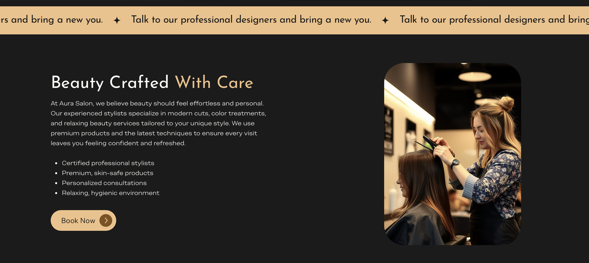 A stylist with long blonde hair styled in a half-up bun, wearing a floral blouse and black apron, is cutting a woman's hair in a modern salon. The woman has long brown hair and is seated in a black salon chair.