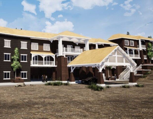 Multi-story residential building with a covered parking area in the foreground, surrounded by dirt and some small plants, under a partly cloudy sky.